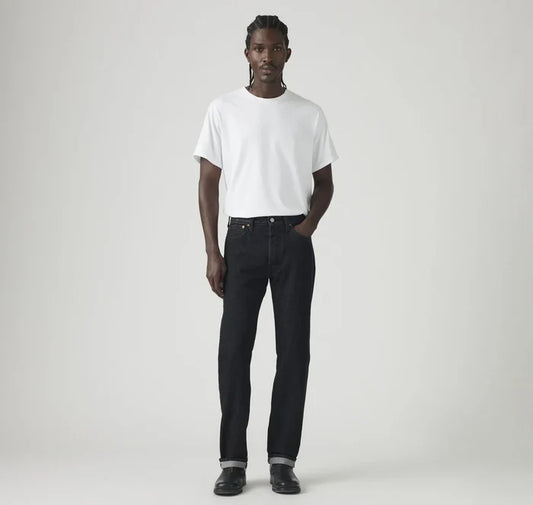 Man wearing a white t-shirt and black jeans on a plain background