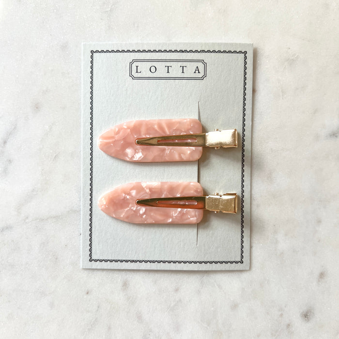 Two pink marbled hair clips with gold bases on a Lotta branded card against a marble background.