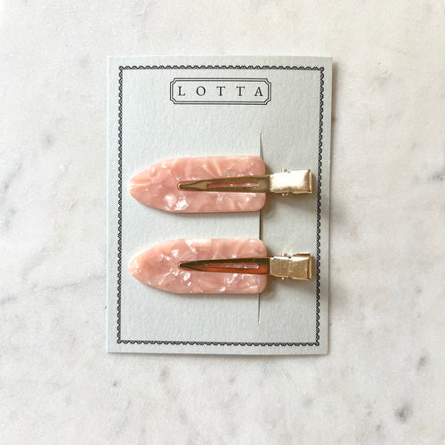Two pink marbled hair clips with gold bases on a Lotta branded card against a marble background.