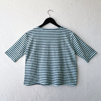 Blue and black striped shirt on a hanger against a white wall, viewed from behind